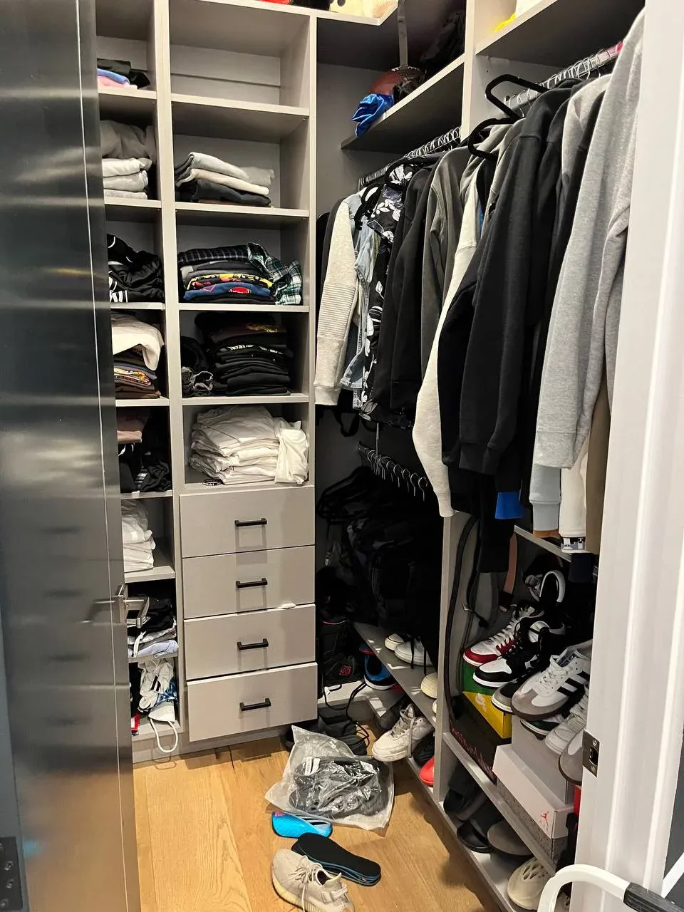 The walk-in before, with the floor covered in shoes and bags and the hanging rod overpacked