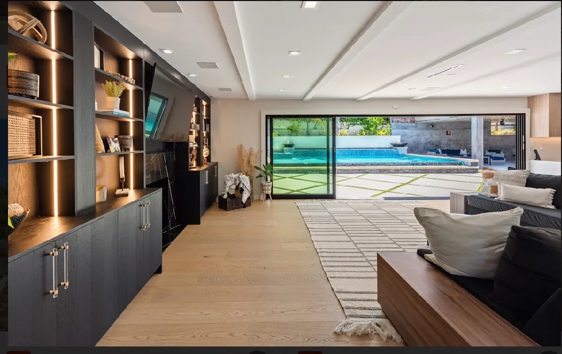 Family room with built-in shelving, dark cabinetry, and sliders opening to the pool deck