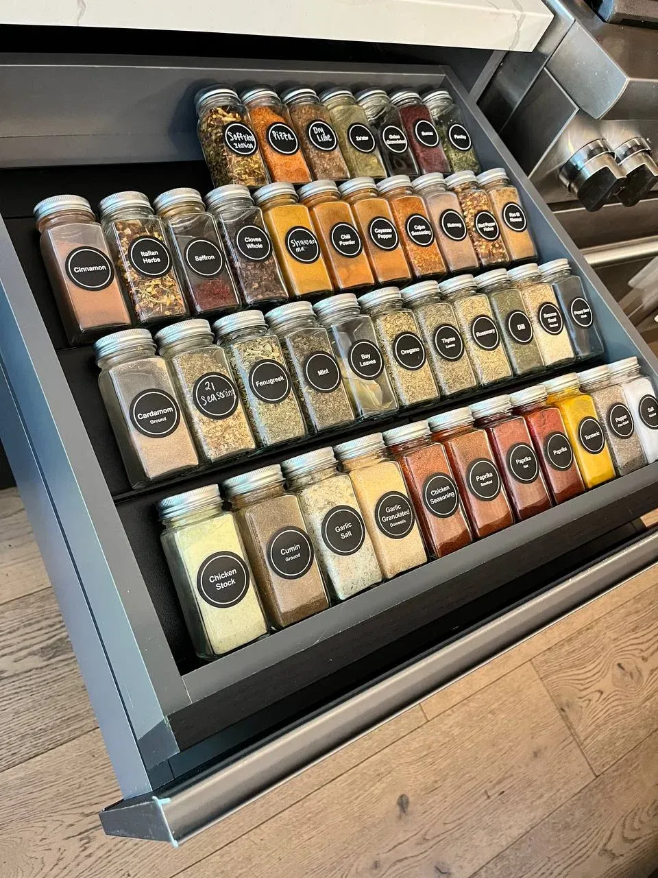 Top-down view of the spice drawer with uniform labeled jars set into a tiered insert