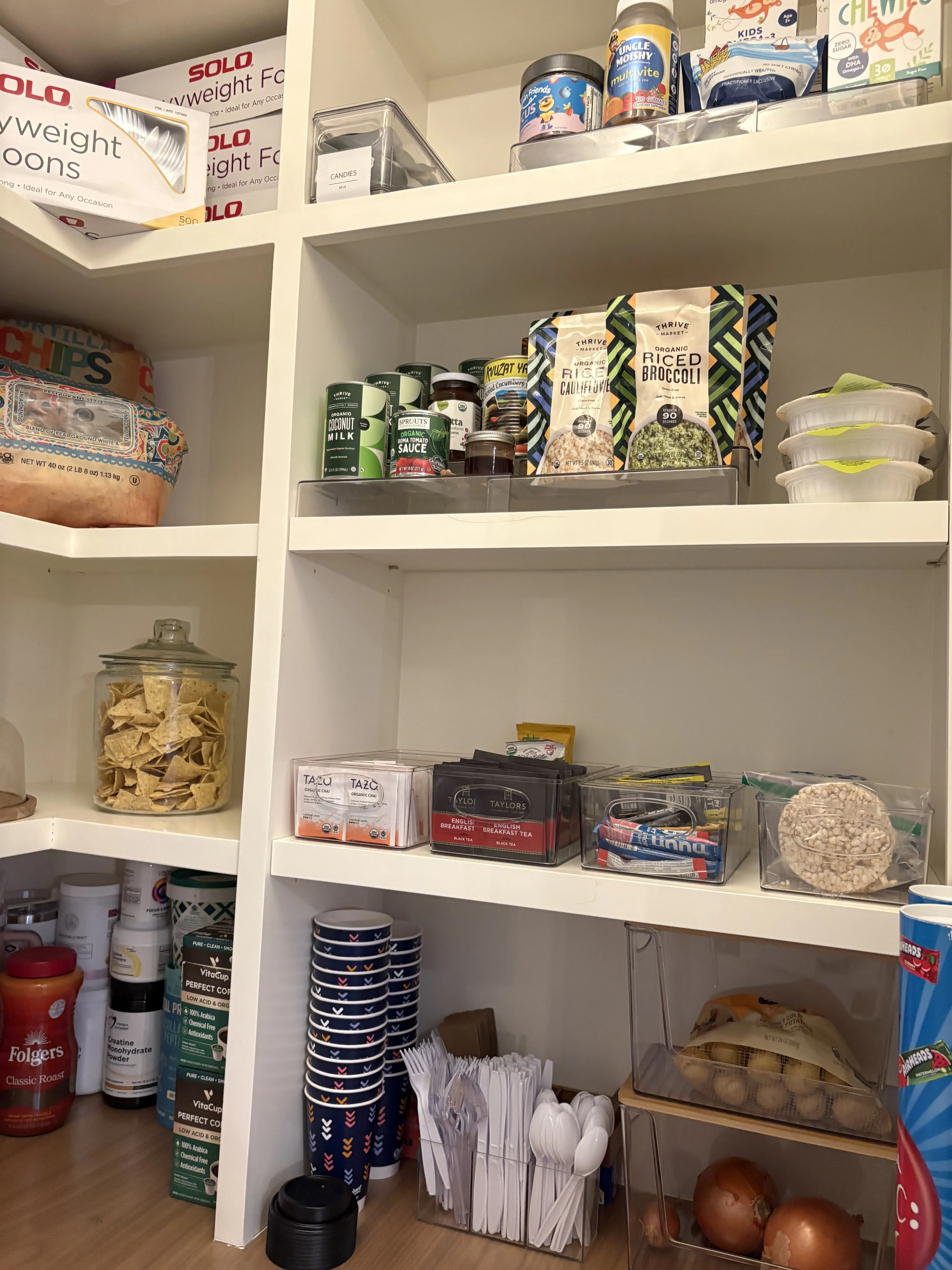 Same corner after, with canned goods on top, snack bins in the middle, a glass jar of tortilla chips, and a low shelf for onions and potatoes