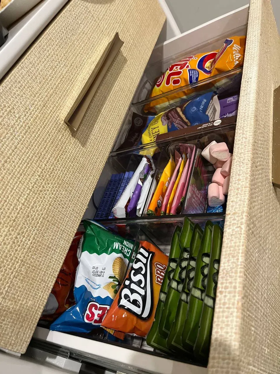 Snack drawer with raffia-fronted panels and clear bins separating chips, candy, and marshmallows