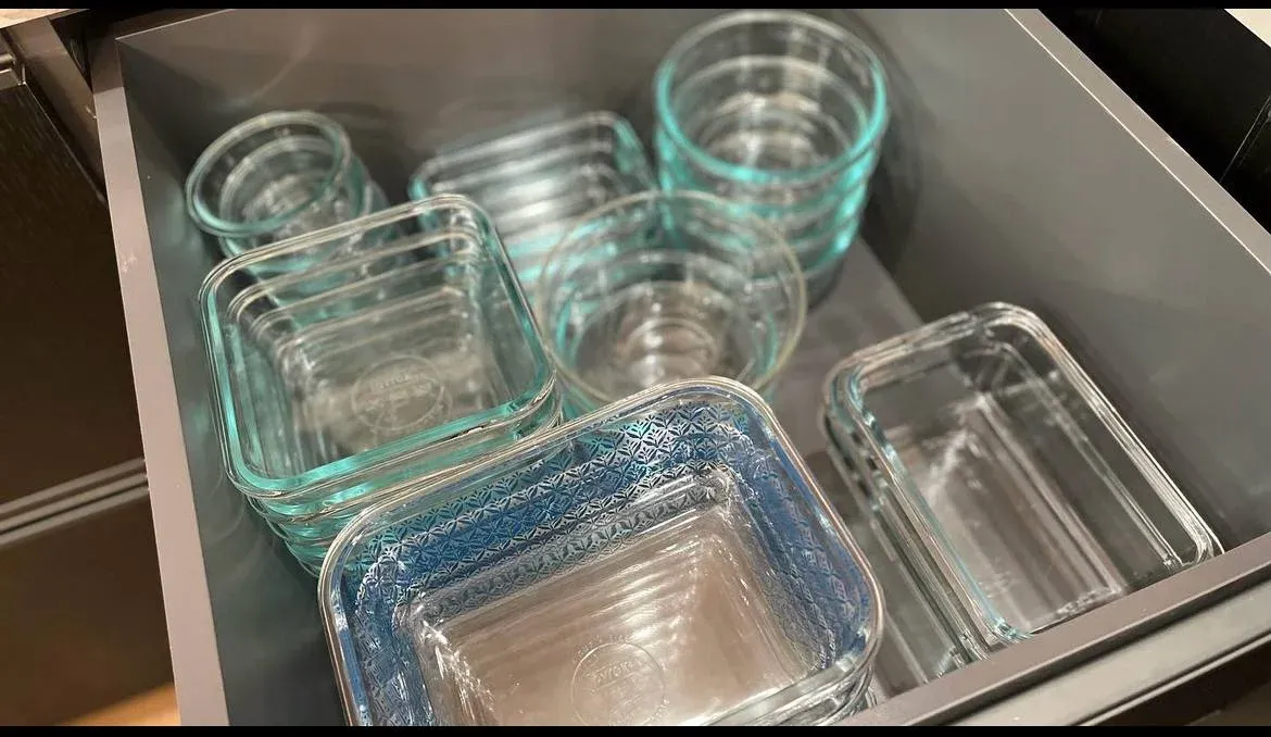 Drawer of glass food-storage containers nested by size with their lids stored alongside