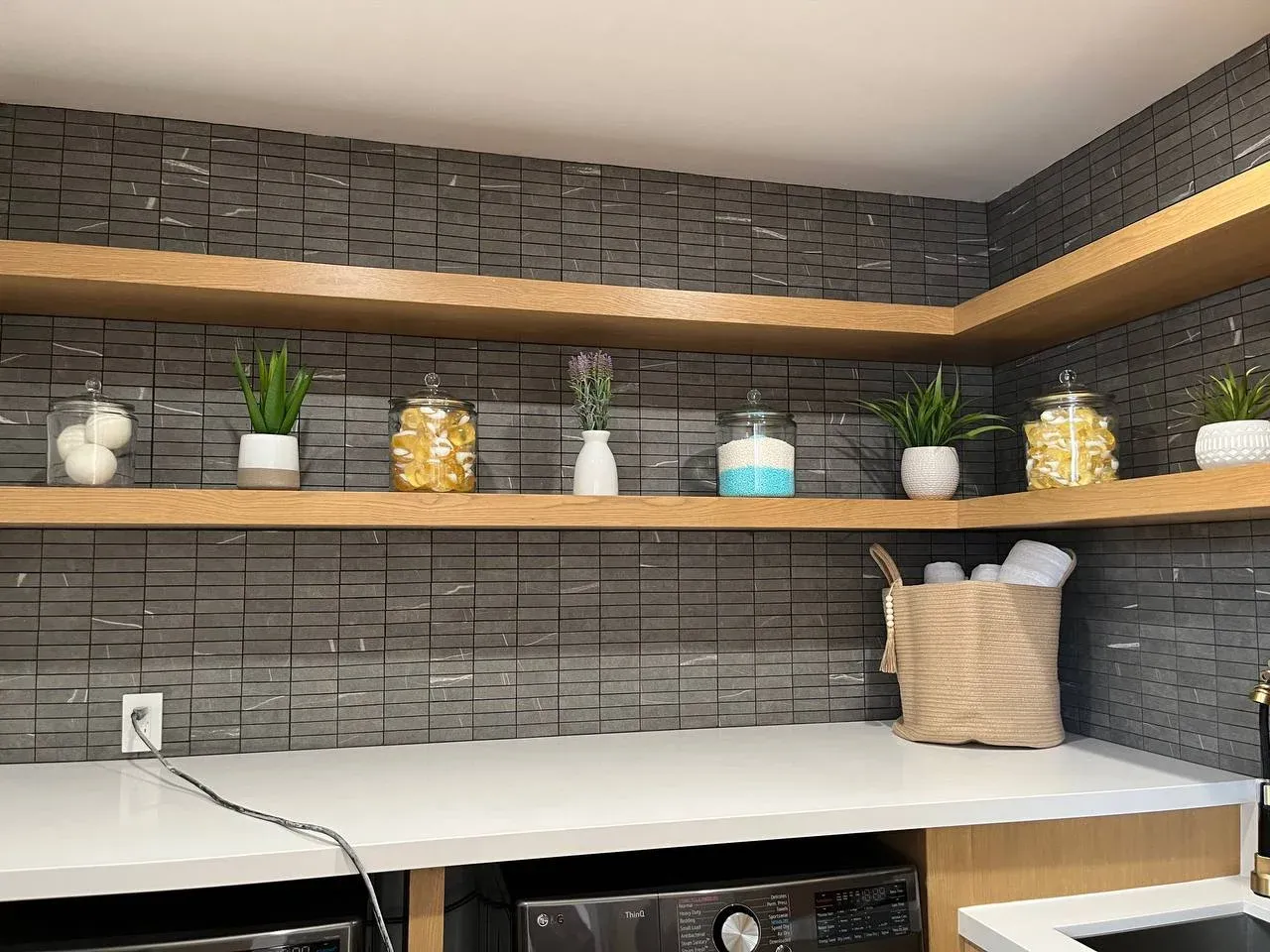 Wider laundry room view with the corner shelves styled and a kraft caddy on the counter