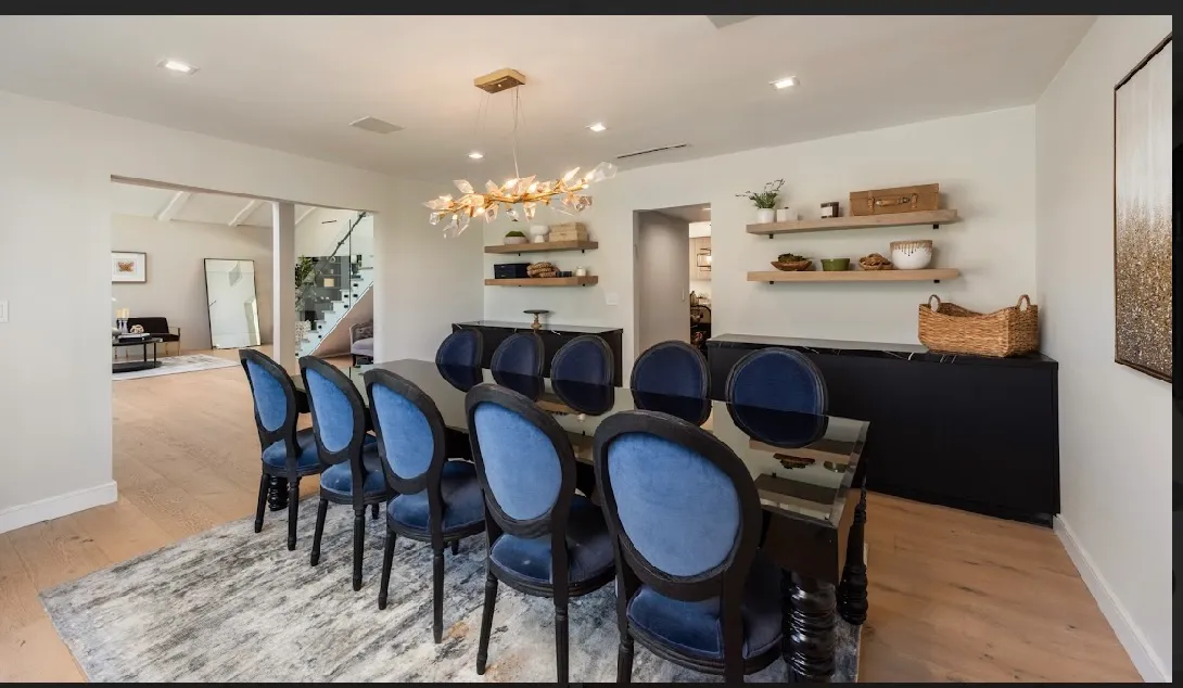 Dining room with a long table, navy upholstered chairs, and floating shelves above a sideboard