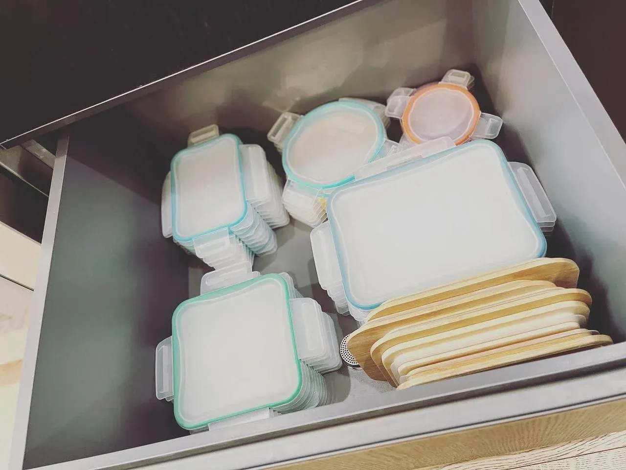 Meal-prep drawer with lock-lid containers nested by size and wooden lids standing on edge