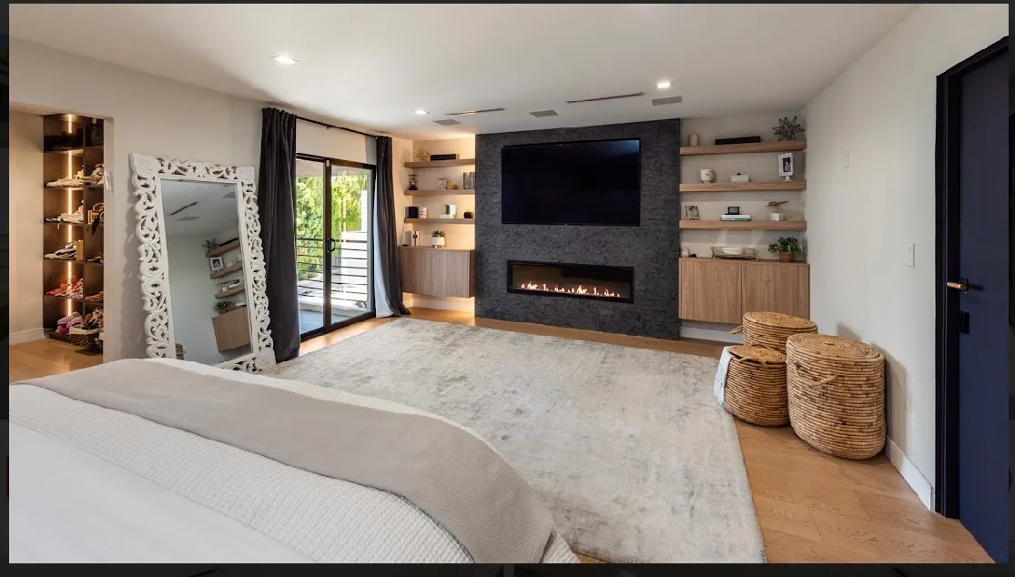 Primary bedroom with a wall-mounted fireplace, built-in shelving, and a leaning floor mirror