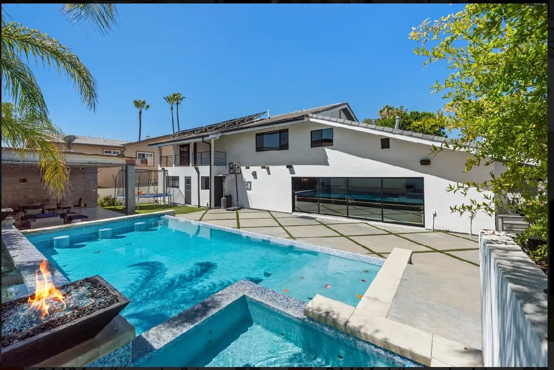 Backyard pool and spa with the house and palm trees in the background