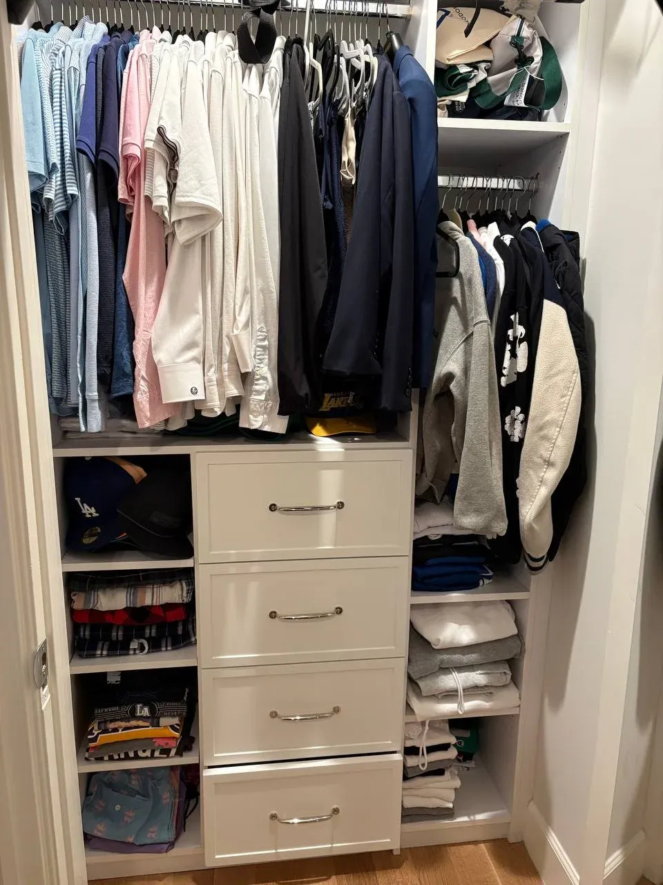 Boy's closet with button-down shirts and polos hanging in blues and whites, folded crewnecks above, and a white drawer tower in the middle