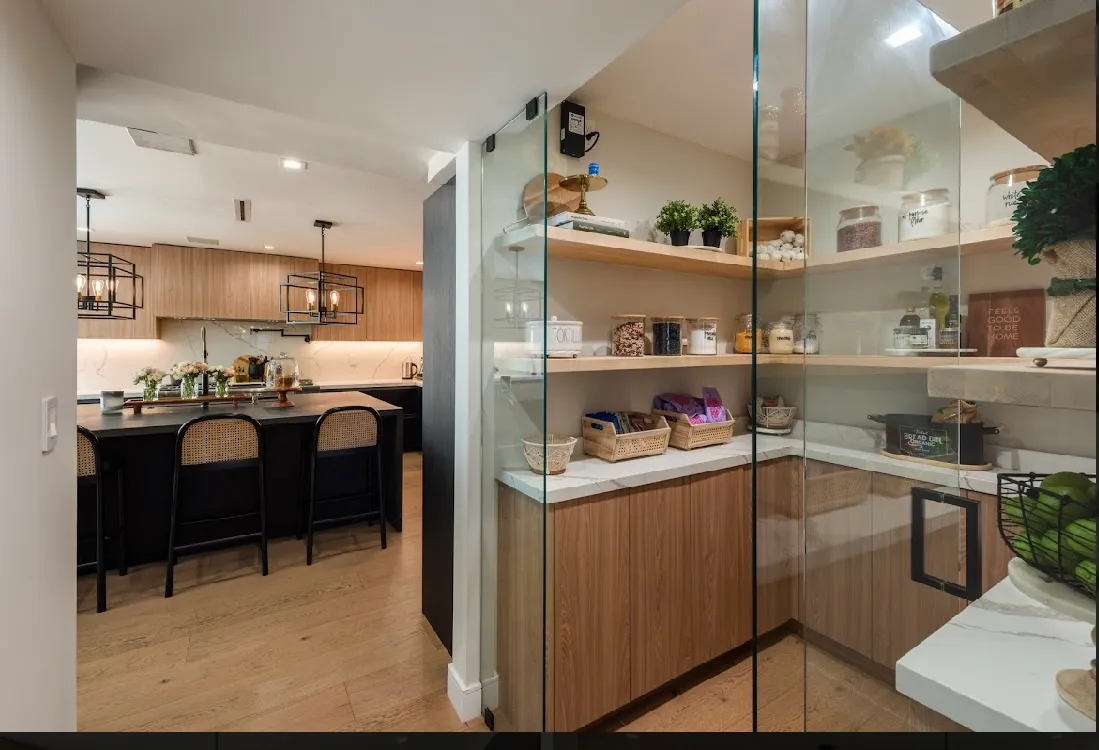 Walk-in pantry with a glass door, butcher-block shelves, and natural light spilling in from the kitchen