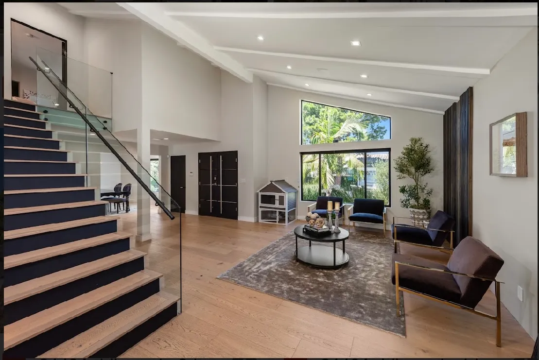 Open-tread floating staircase set against a feature wall, with the great room flowing past underneath