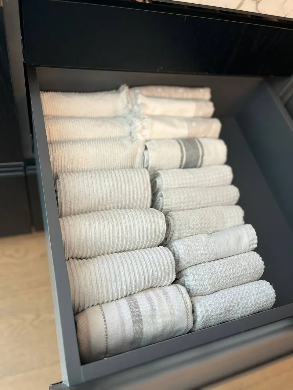 Drawer of kitchen towels each rolled and stood on end so the edges read like a row of files